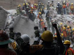 Con el puño levantados, los topos y más rescatistas piden silencio para escuchar posibles víctimas. EFE / S. Gutiérrez