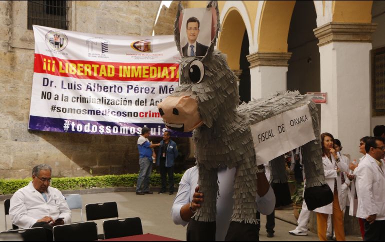 Médicos exhiben una piñata de asno con la leyenda 