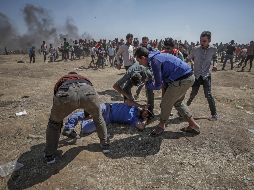 Manifestantes palestinos tratan de ayudar a un herido durante enfrentamientos tras una protesta cerca de la frontera con Israel. EFE/M. Saber