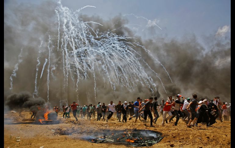 Palestinos huyen del gas lacrimógeno durante enfrentamientos con fuerzas de seguridad israelíes el 14 de mayo, cerca de la frontera de Israel y la Franja de Gaza, en una protesta de palestinos por la inauguración de la embajada estadounidense en Jerusalén. AFP/M. Abed