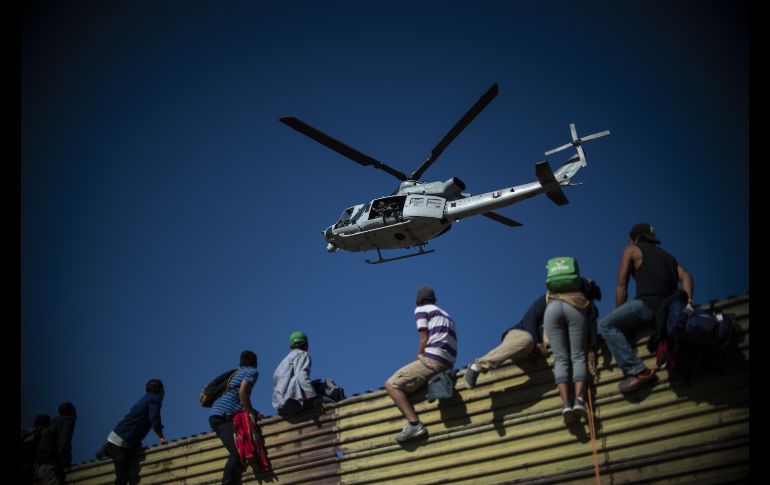 Un grupo de centroamericanos sube la valla fronteriza entre Tijuana, México, y San Diego, Estados Unidos, eñ 25 de noviembre. Autoridades de EU arrojaron luego gas lacrimógeno para evitar el avance de integrantes de la caravana migrante. AFP/P. Pardo