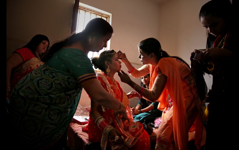 Familiares arreglan a una novia previo a una ceremonia de boda para ocho parejas en Nueva Delhi, India. Los matrimonios masivos se organizan para ayudar a las familias que no pueden costear las ceremonias caras y dotes que aún se acostumbran en muchas comunidades. AP/A. Qadri