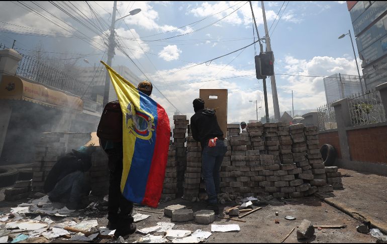 Manifestantes se ocultan tras una barricada cuando se cumplen 10 días de protestas contra el Gobierno este sábado, en Quito. EFE/J. Jácome