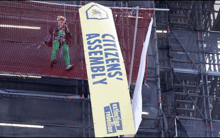Tras subir sin protección por andamios instalados en Houses of Parliament, sede del parlamento británico, el militante disfrazado de Boris Johnson desplegó pancartas. AP/K. Wigglesworth