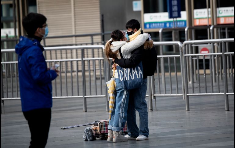 Una pareja con mascarillas se abraza este lunes en una estación de trenes en Shanghái, China. AFP/N. Celis