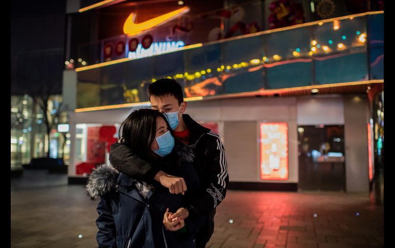 En un intento por contener el virus, autoridades chinas han suspendido los transportes de ciudades enteras e implementado el uso de mascarillas. Unos jóvenes se abrazan en un centro comercial vacío en Pekín. AFP/N. Asfouri