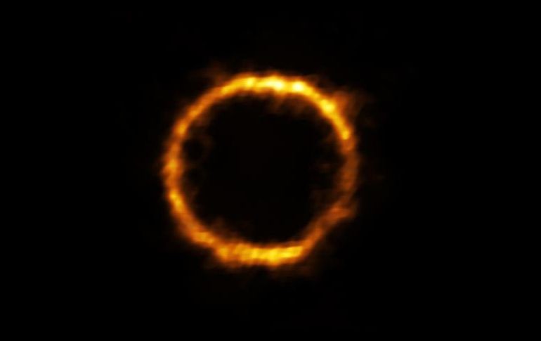 SPT0418-47 luce como un hermoso anillo de luz sobre fondo negro. AFP /
