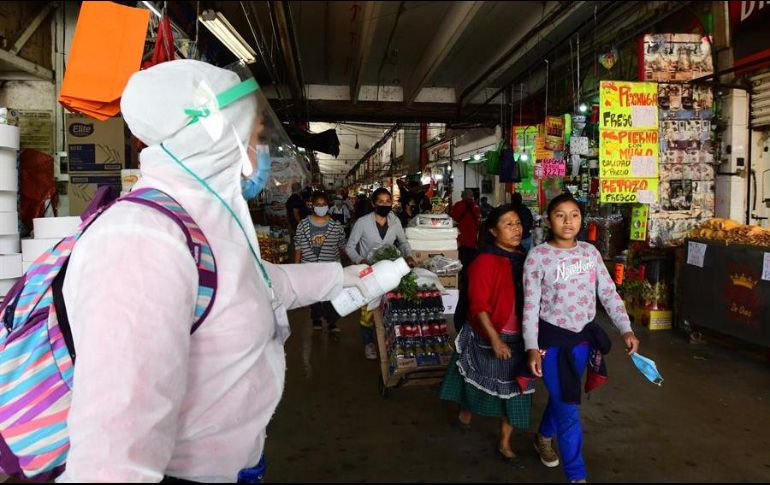 Una empleada de la salud ofrece gel antibacterial a personas en un mercado de la Ciudad de México. EFE/J. Núñez