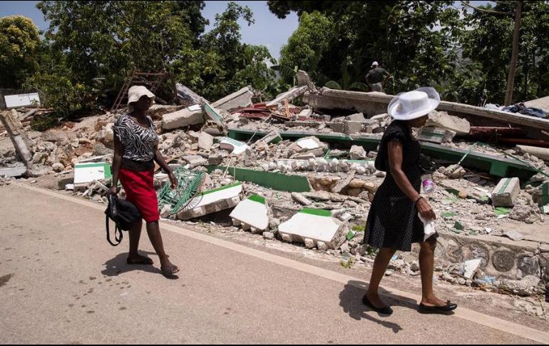 Dos mujeres caminan junto a una vivienda derrumbada durante el terremoto del pasado 14 de agosto, hoy, en Marceline, Haití. EFE/O. Barría