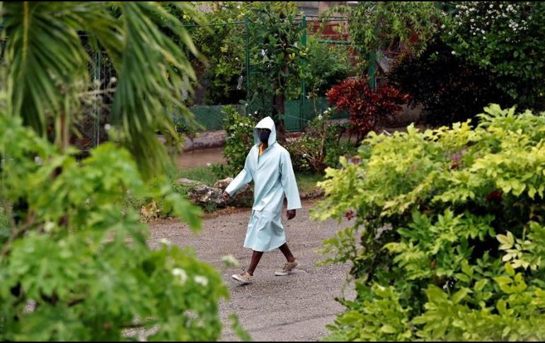Un hombre camina bajo la lluvia protegido con una capa impermeable en La Habana. EFE/E. Mastrascusa
