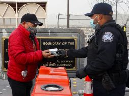 Un agente estadounidense de Protección Fronteriza y Aduanas solicita el certificado de vacunación anti COVID-19 a un hombre que quieren cruzar de Ciudad Juárez a El Paso. AFP/H. Martínez
