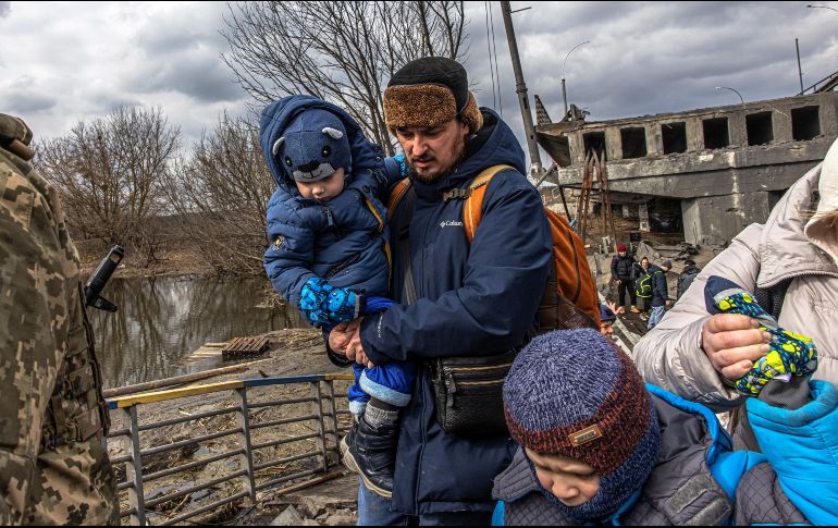 Ucranianos con bebés y niños cruzan un puente destruido tras ataques rusos. EFE / R. Pilipey