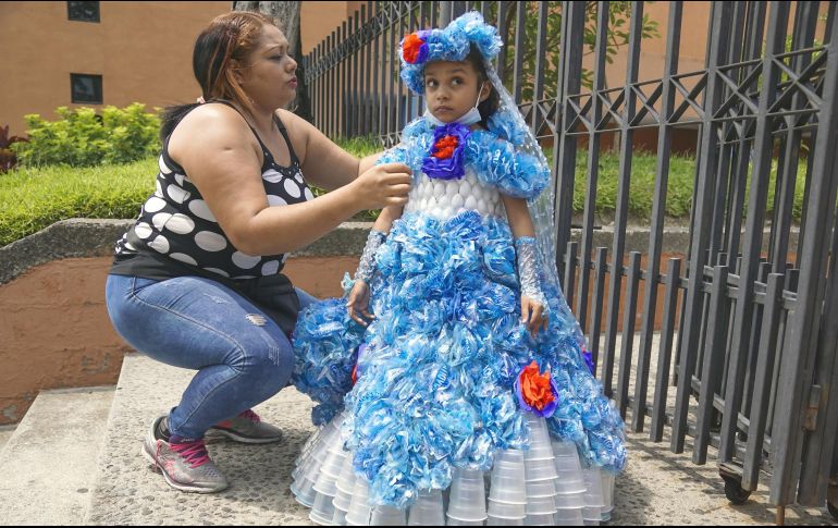 Evelyn Renderos, de 34 años de edad, arregla el vestido de su hija realizado con material reciclado durante un desfile en el marco del Día Mundial del Reciclaje. XINHUA/A. Peña