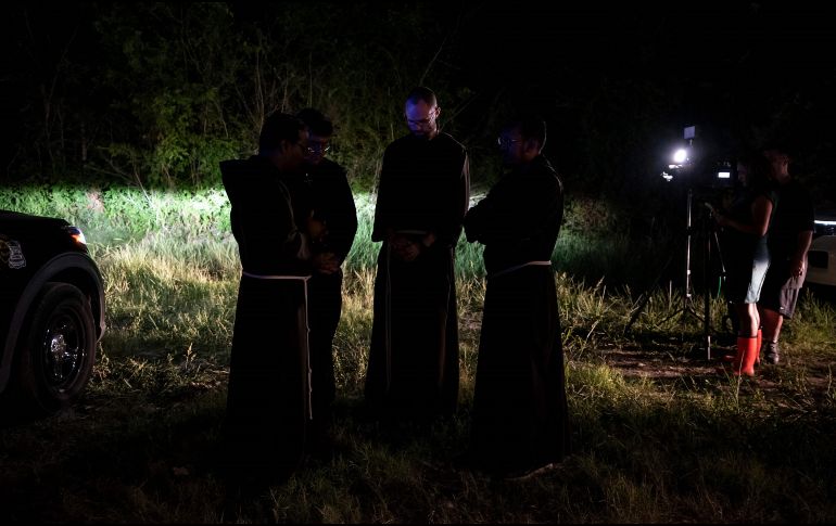 Sacerdotes de la Arquidiócesis de San Antonio permanecen en oración cerca del lugar donde se encontró el tráiler con los cuerpos de los migrantes. AFP / S. Flores