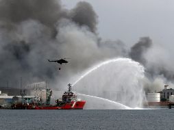 El buque Bourbon Artabaze, de la armada mexicana, lanzando un potente chorro de agua a unos 150 metros del fuego mientras que helicópteros dejan caer agua de mar. EFE / E. Mastrascusa