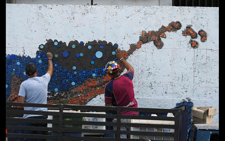 Cuatro guacamayas rojas en vuelo y un turpial, el ave nacional de Venezuela, son motivos estrella en la obra. AFP/F. Parra