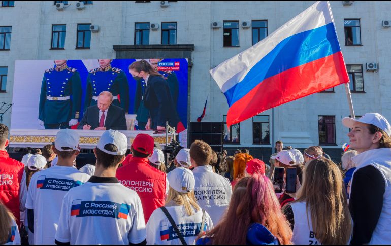 Habitantes ven una transmisión en vivo de la ceremonia para firmar tratados sobre la adhesión de nuevos territorios a Rusia en el centro de Luhansk, Ucrania. EFE