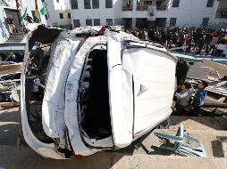 Unos palestinos observan un vehículo destrozado a causa de una incursión militar del Ejército israelí en el campo de refugiados de Yenín. EFE/A. Badarneh