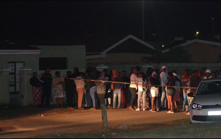 Una multitud de curiosos se congregó el lunes fuera de la casa donde se produjo el tiroteo. AFP/L. Mehlwana