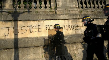 Policías patrullando junto a un grafitti con la leyenda 