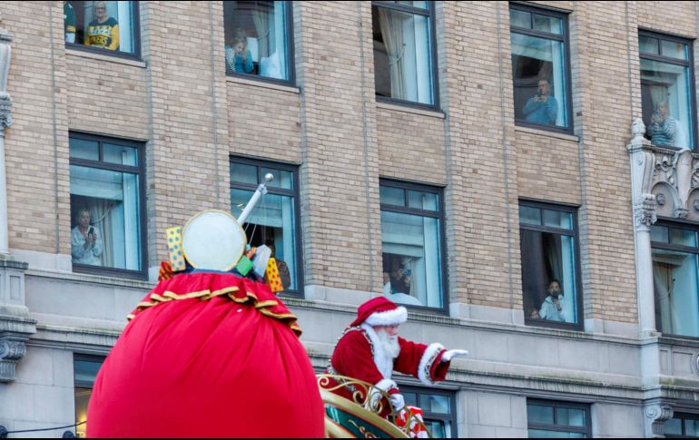 La gente observa desde las ventanas cómo pasa Santa Claus. EFE / S. Yenesel