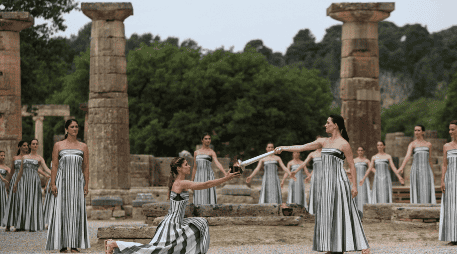 Una actriz vestida como una sacerdotisa griega utiliza el sol para prender una antorcha plateada tras ofrecer una oración simbólica a Apolo, el antiguo dios griego del Sol. EFE / G. Vitsaras