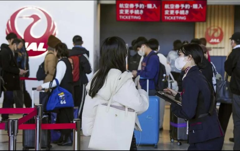 Una trabajadora de la aerolínea Japan Airlines ayuda a viajeros en el Aeropuerto Internacional de Osaka, luego de que la compañía anunció que había sufrido un ciberataque. AP