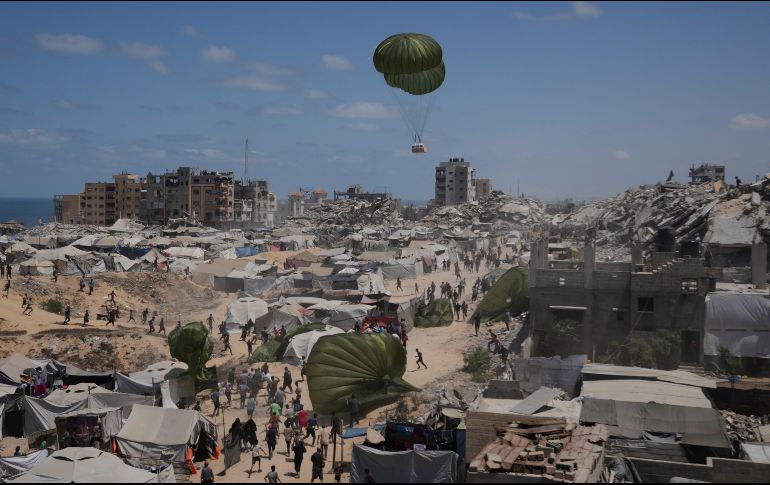 Palestinos en la Ciudad de Gaza corren para recoger ayuda humanitaria lanzada con paracaídas desde el aire. La toma de la capital desplazaría a un millón de personas, muchas de ellas llegadas de otras zonas ya ocupadas. AP/J. Alshrafi