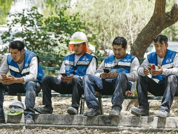 Trabajadores revisan sus teléfonos celulares durante la prueba piloto de registro de líneas móviles. EL UNIVERSAL