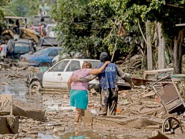 Un elemento de la Marina de México ayuda a una mujer a cruzar una calle inundada en Poza Rica, Veracruz. AP