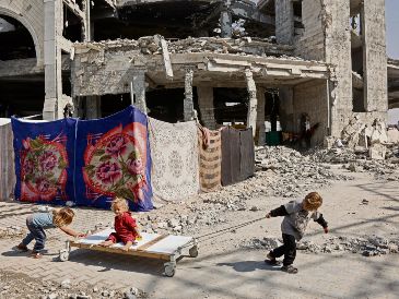 Un grupo de niños juega entre los escombros de la ciudad palestina, ajenos a la tensión entre Israel, Hamás y Estados Unidos. AFP