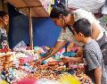 Una mujer y su hijo adquieren artículos para su altar de Día de Muertos, tradición que impulsa la economía local. EL INFORMADOR