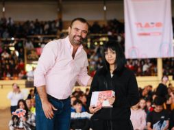 El presidente municipal, Gerardo Quirino Velázquez Chávez, entrega una tableta electrónica a una de las estudiantes destacadas durante el evento en el lienzo charro Santa María. X/GerardoQuirinoV