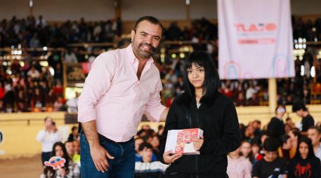 El presidente municipal, Gerardo Quirino Velázquez Chávez, entrega una tableta electrónica a una de las estudiantes destacadas durante el evento en el lienzo charro Santa María. X/GerardoQuirinoV
