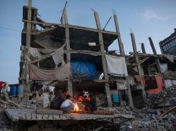 Desplazados palestinos junto a un fuego en los restos de un edificio en Kah Yunis. EFE / EPA / HAITHAM IMAD