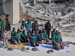Un grupo de voluntarios basijis -milicia islámica- reza este miércoles, al lado de un edificio destruido en los bombardeos israelíes-estadounidenses contra Irán en la calle en la calle Kargar, cerca de la plaza Engelab en Teherán. EFE/ J. León