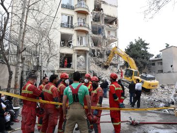 Bomberos y funcionarios iraníes trabajan en el lugar donde se encuentran los edificios residenciales dañados en el norte de Teherán, Irán, el 23 de marzo de 2026. EFE/A. TAHERKENAREH