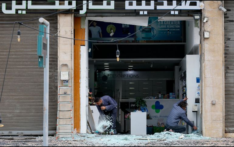 Trabajadores limpian los cristales rotos de una farmacia tras un ataque israelí en la zona de Al Chiyah, un suburbio al sur de Beirut, Líbano. EFE/W. Hamzeh