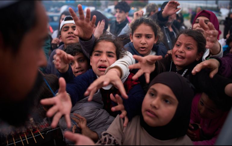 Familias desplazadas extienden las manos mientras esperan a recibir donativos de alimentos en un campamento después de huir de los bombardeos israelíes en el sur de Líbano. AP/E. Morenatti