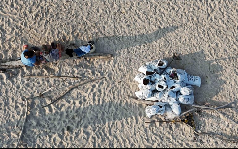 Trabajadores descansan después de llenar costales con arena contaminada con petróleo. El derrame reportado desde inicios de febrero de 2026, y que todavía sigue dejando estragos, se originó por una fuga detectada en uno de los ductos del complejo Cantarell. SUN/D. Prado