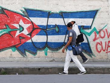 Personas caminan frente a un mural con la bandera de Cuba en La Habana. EFE/E. Mastrascusa