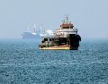 Remolcador iraní navega cerca de un buque anclado en el Estrecho de Ormuz, frente a Bandar Abbas; Teherán niega paso de barcos comerciales. AFP