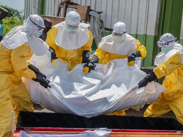 Trabajadores de la Cruz Roja colocan en un ataúd el cuerpo de una persona que murió de ébola, en un centro de salud en Rwampara, Congo. AP/M. Sawasawa