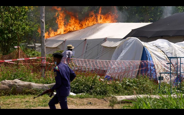 Un guardia de seguridad corre frente a un centro de tratamiento del ébola en llamas en Rwampara, República Democrática del Congo. AP/D. Lotsima