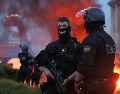 Un automóvil arde y estallan fuegos artificiales mientras la policía observa a los aficionados del PSG celebrar en París. AP/T. Padilla