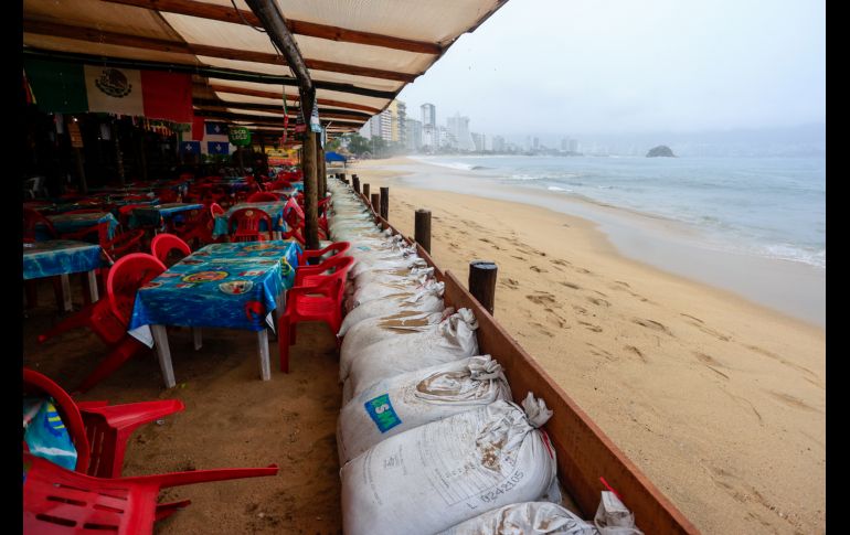 Personas protegen un negocio con costales pesados ante el pronóstico de fuertes lluvias este lunes, en Acapulco. EFE/D. Guzmán