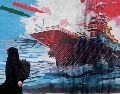 Una mujer pasa junto a un mural que muestra un portaaviones estadounidense bajo ataque en el centro de Teherán, Irán, el lunes 8 de junio de 2026. AP/Vahid Salemi
