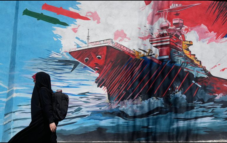 Una mujer pasa junto a un mural que muestra un portaaviones estadounidense bajo ataque en el centro de Teherán, Irán, el lunes 8 de junio de 2026. AP/Vahid Salemi