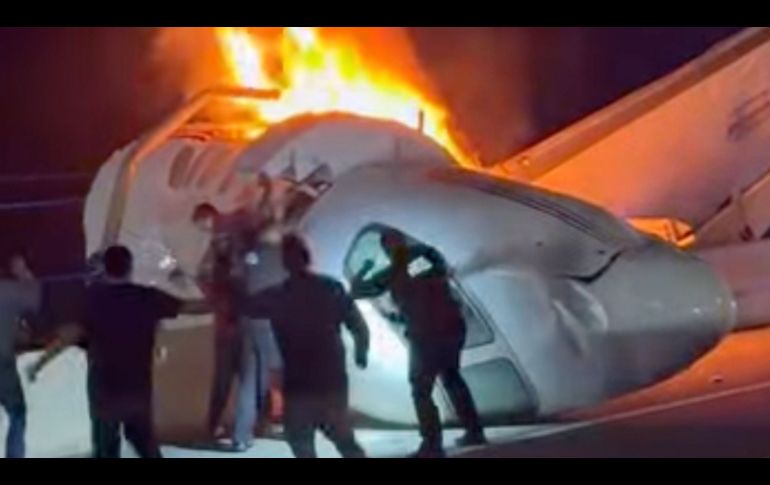 Un pasajero, en la parte superior de la imagen, salta de un avión que se estrelló en una autopista de Texas mientras otras personas ayudan. AP/Z. Garza