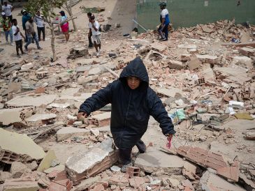 Un niño camina este jueves, entre los escombros de edificios afectados por los terremotos en La Guaira, Venezuela. EFE/ R. Peña